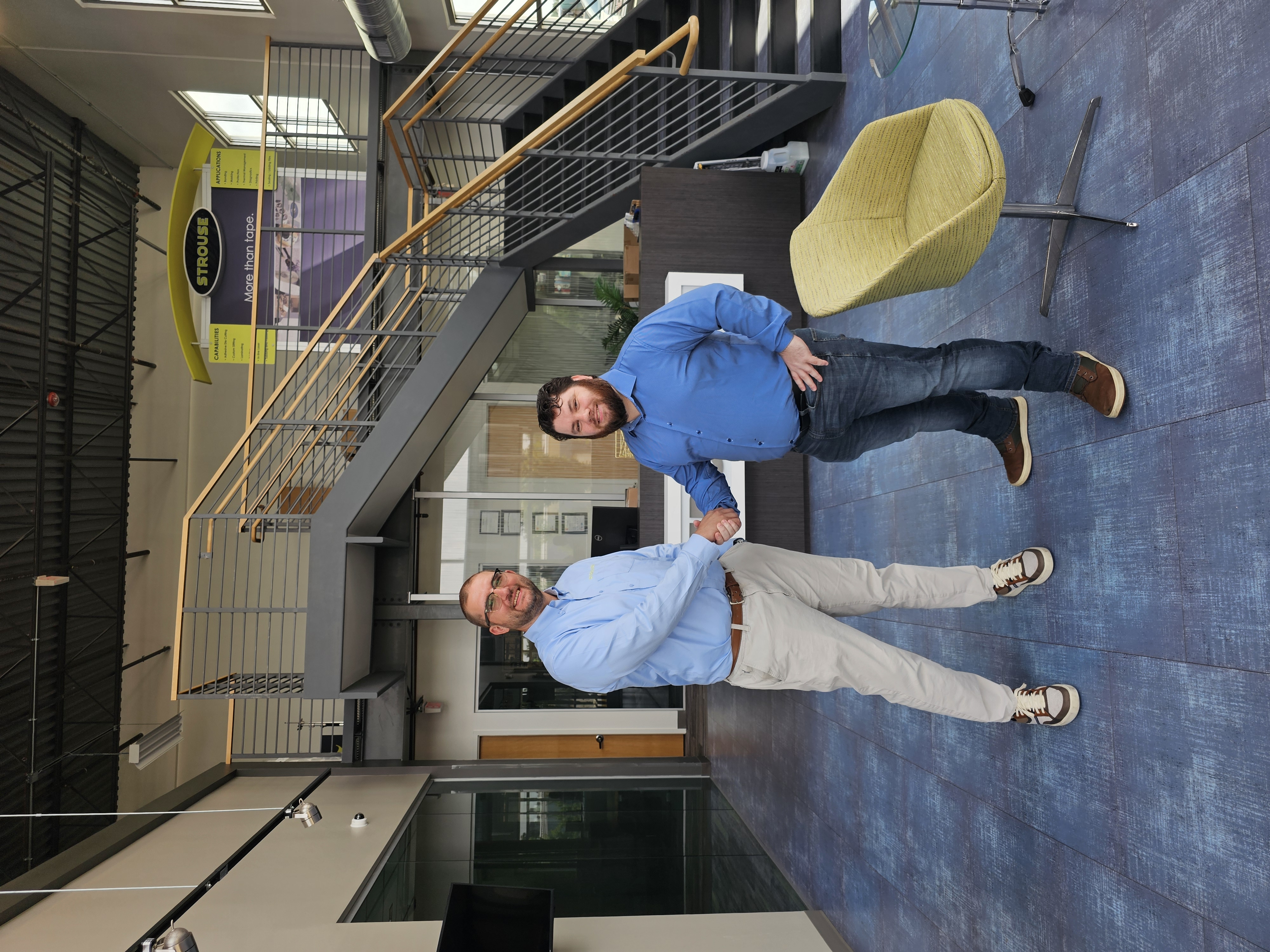 Representatives from AXOLTL and The Strouse Corporation shaking hands in the Strouse headquarters lobby